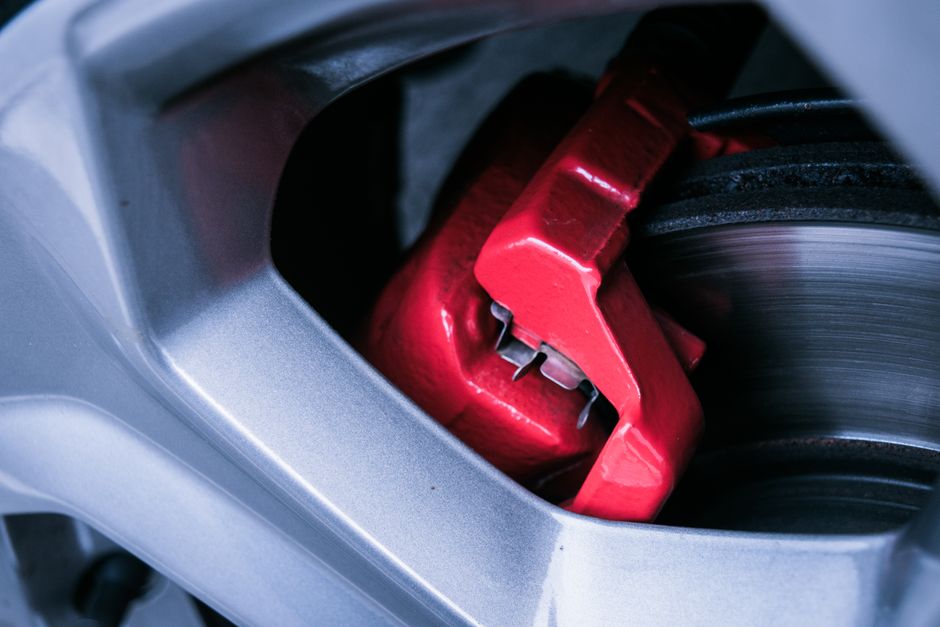 Detailed photo of a red automotive brake caliper and disc brake in focus.